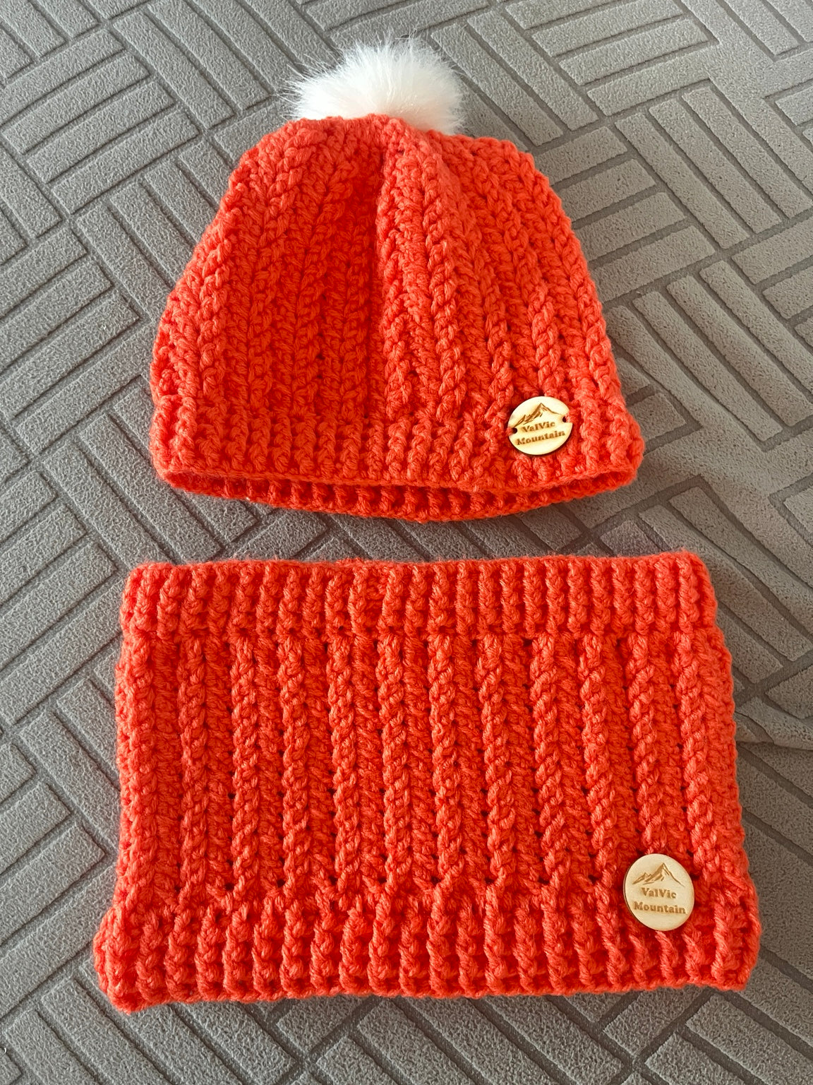 Ensemble ValVic Mountain orange au crochet : bonnet à pompon blanc et tour de cou assorti avec étiquettes rondes.
